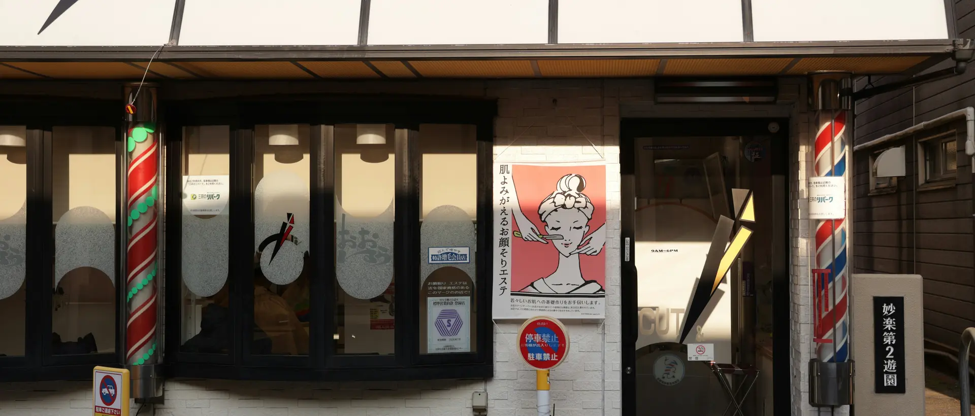 Fachada de una barbería con poste y toldo